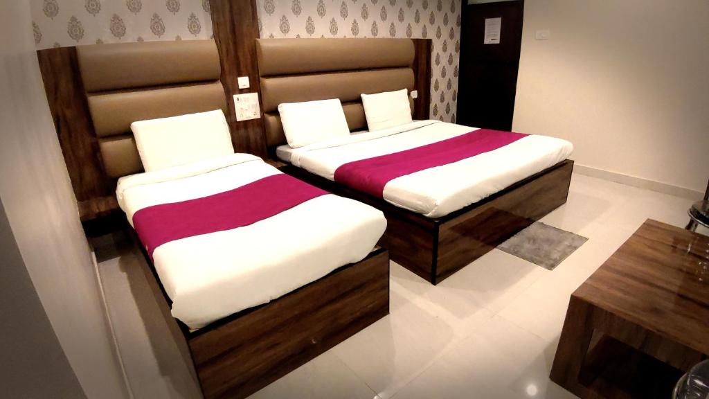 duas camas sentadas uma ao lado da outra num quarto em City Hotel em Allahabad