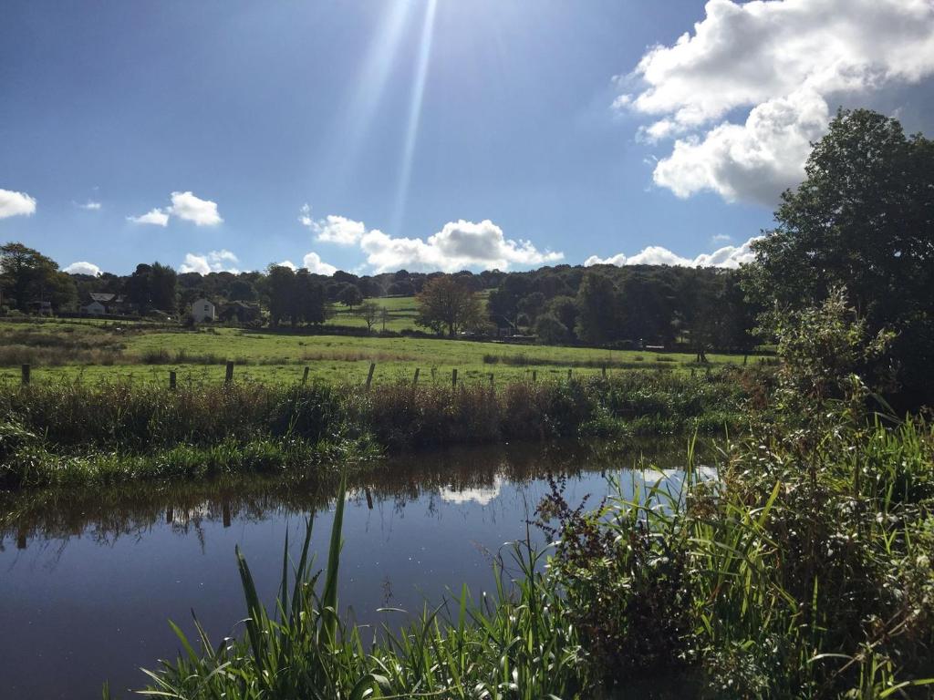 a pond in a field with the sun in the sky at Serenity- Uk38551 in Endon