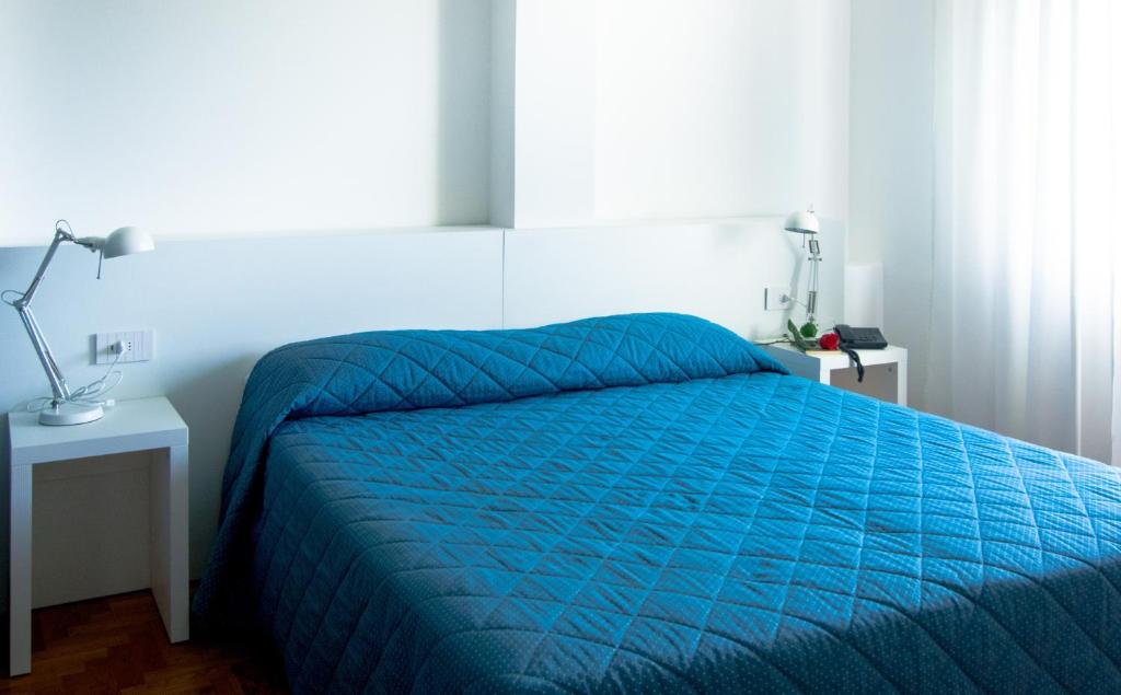 Hotel Mistral في أوريستانو: سرير مع لحاف أزرق في غرفة النوم