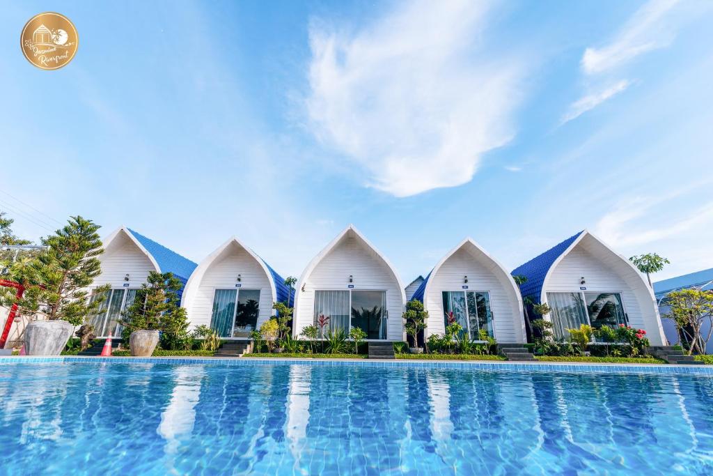 una fila de cabañas de playa blancas con piscina en Jasmine River Front, en Kampot