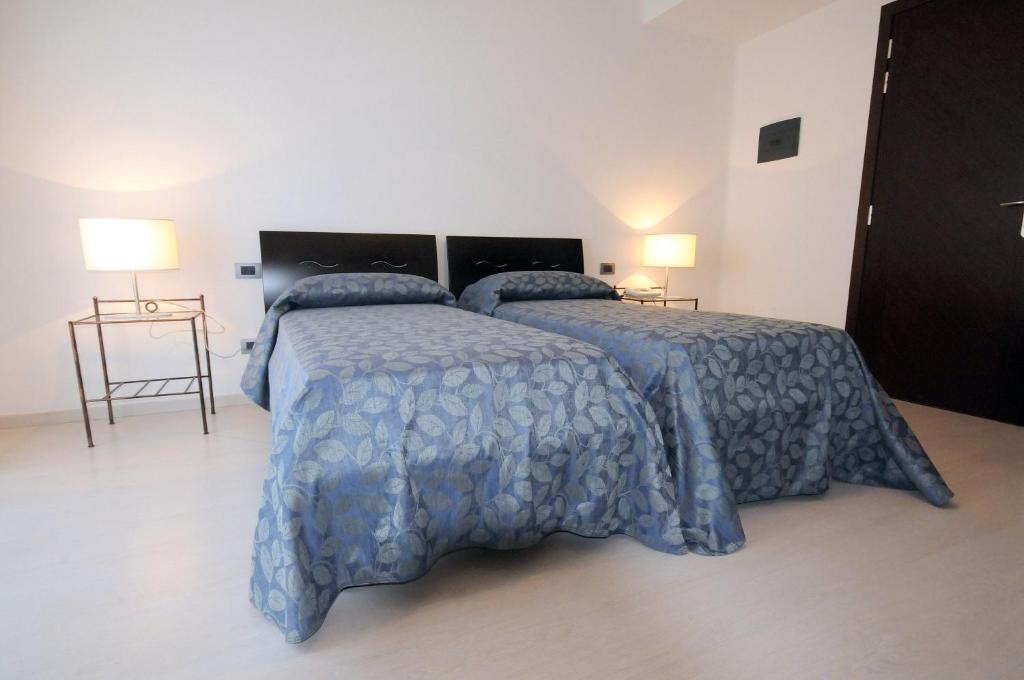 a bedroom with two beds with blue comforter and lamps at Hotel Sorriso in Venice-Lido
