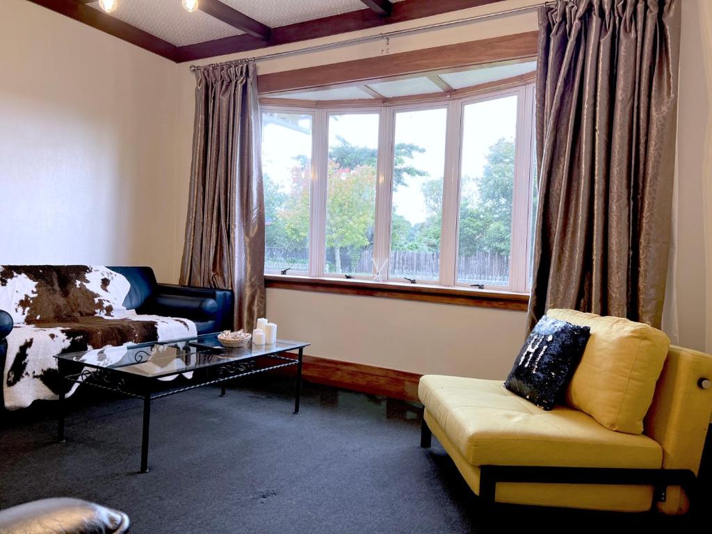 a living room with a couch and a table and a window at Rotorua Holiday Villa in Rotorua