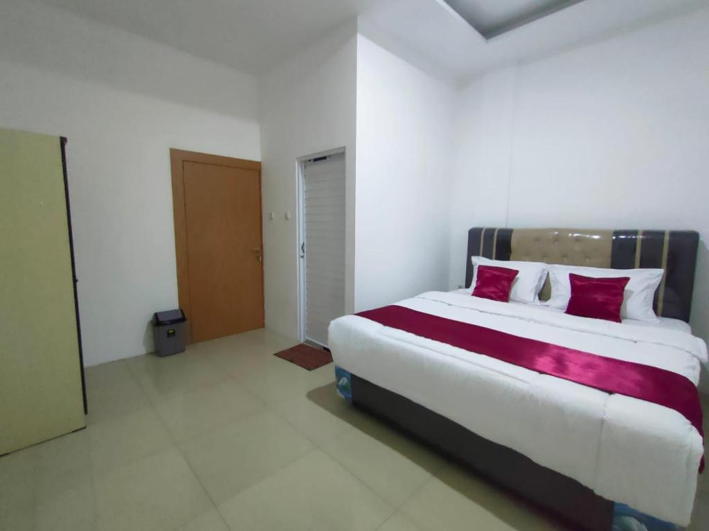 ein Schlafzimmer mit einem großen weißen Bett mit roten Kissen in der Unterkunft Hiast Syariah Residence in Palembang