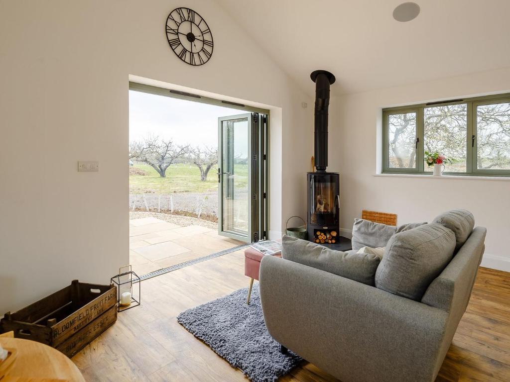 a living room with a couch and a clock on the wall at Bramley Cottage in North Weald