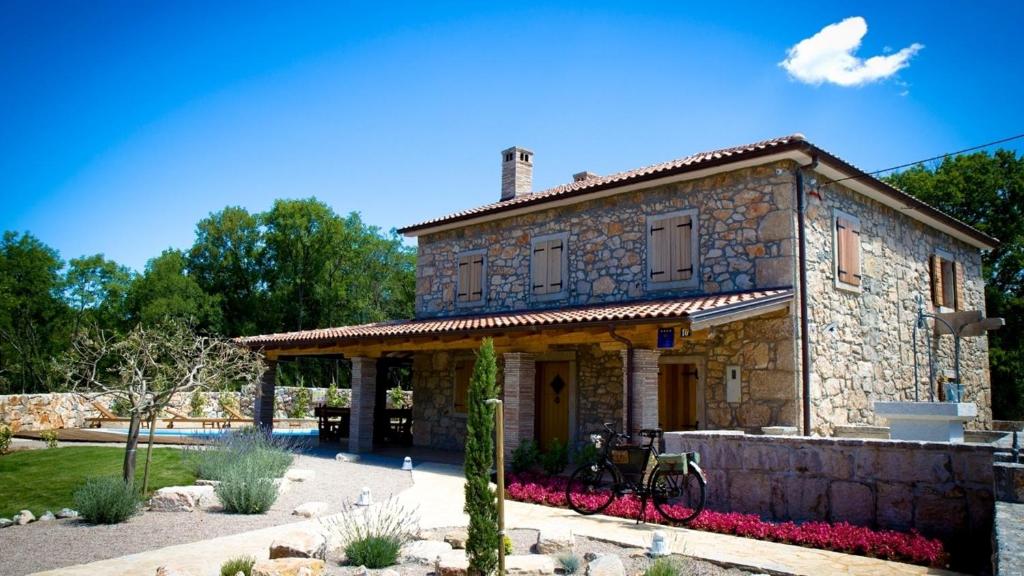 Dobrinj的住宿－Villa Rustica，一座大型石头房子,前面设有一个花园