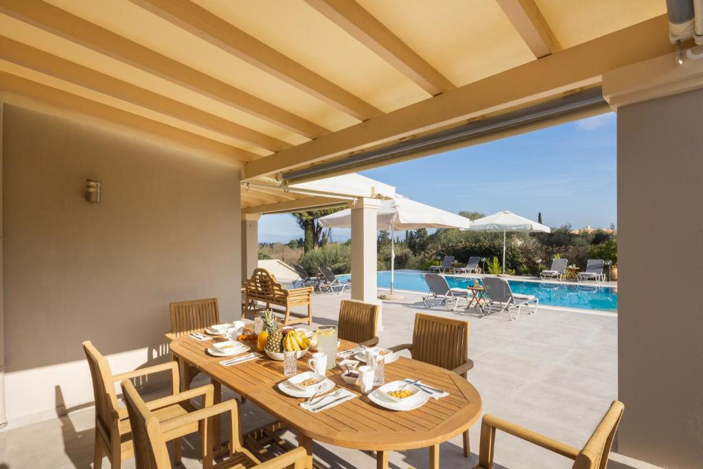 a dining room with a table and chairs and a pool at VILLA SORELLINA in Gouvia