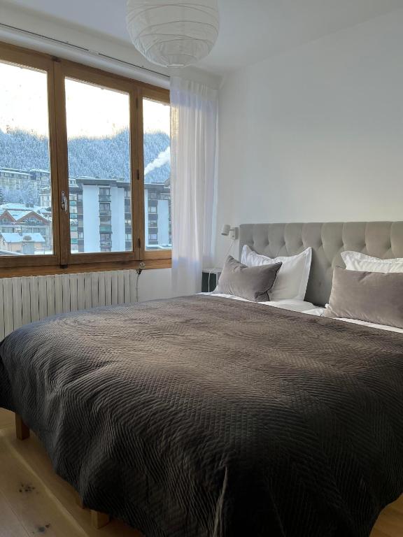 une chambre avec un grand lit avec une grande fenêtre dans l'établissement Appartement Oliver, à Chamonix-Mont-Blanc
