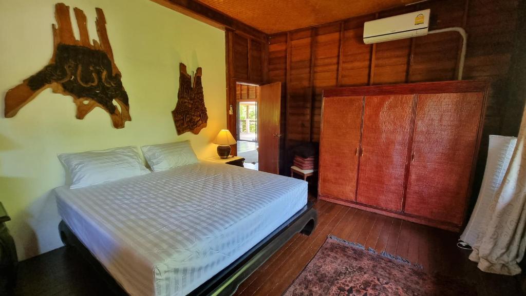 1 dormitorio con 1 cama y pared de madera en BEACH HOUSE WOODY, en Laem Sor