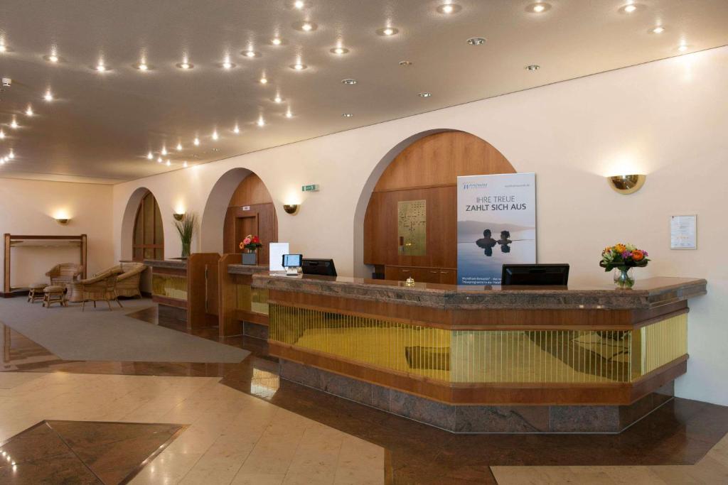 a lobby with a reception desk in a building at Wyndham Garden Donaueschingen in Donaueschingen
