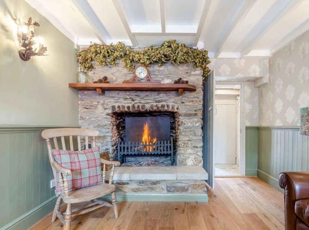 a living room with a stone fireplace with a chair at Rosemary Cottage in Bere Alston