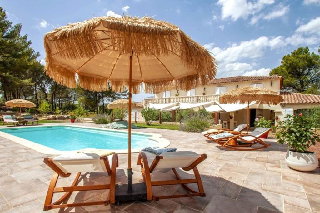 um pátio com cadeiras, um guarda-sol e uma piscina em O' Cocooning - Appart dans Bastide proche Aix em Rousset