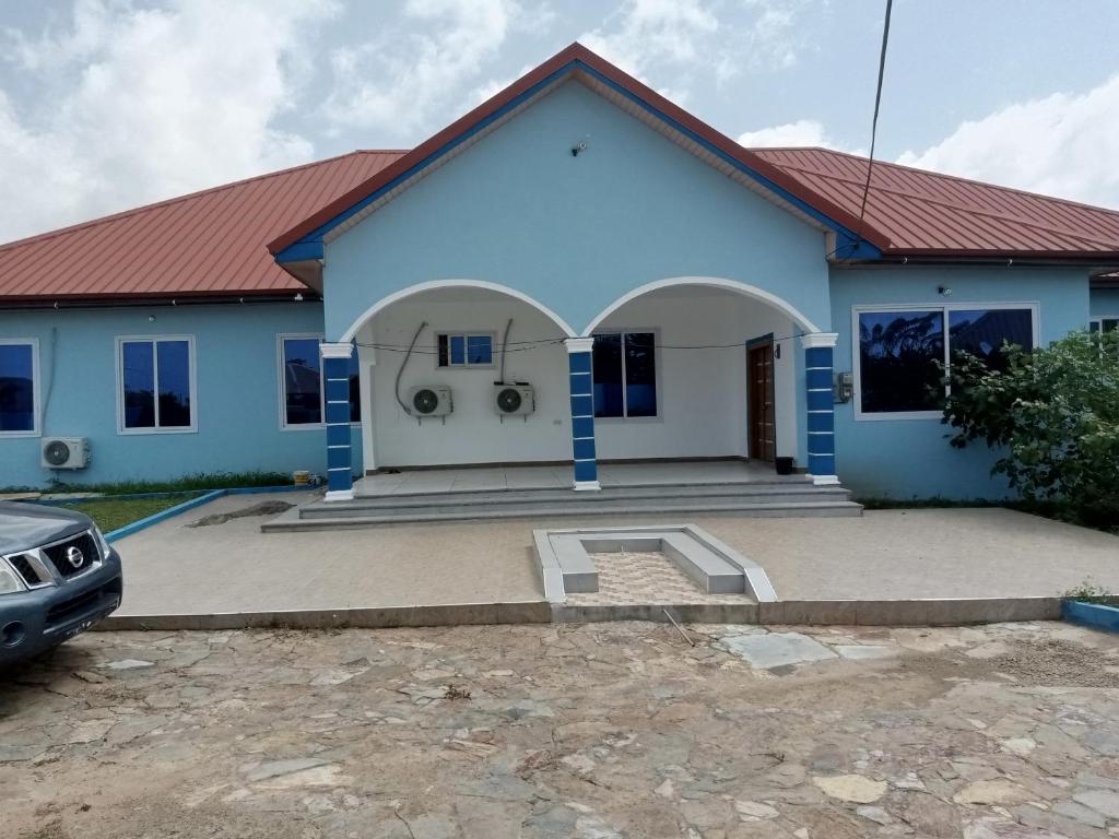 a blue house with a car parked in front of it at Dexxy's Palace Hotel in Koforidua