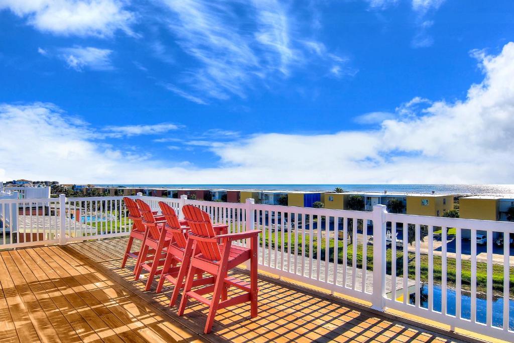 three chairs sitting on a deck overlooking the water at Ruby Redbird Roost in Port Aransas