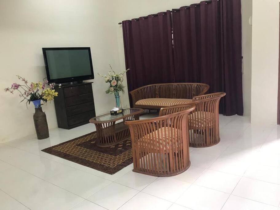 a living room with wicker chairs and a television at HJ Homestay in Kuala Terengganu