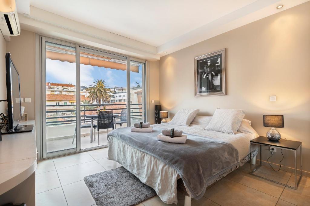 une chambre avec un grand lit et un balcon dans l'établissement Palais Rouaze Cannes, à Cannes