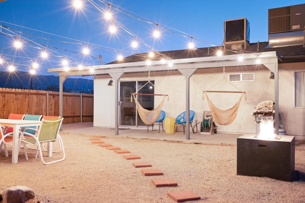 a patio with a table and chairs and lights at The RockHopper - Hot Tub, Fire Pit & Walk to Downtown JT! home in Joshua Tree