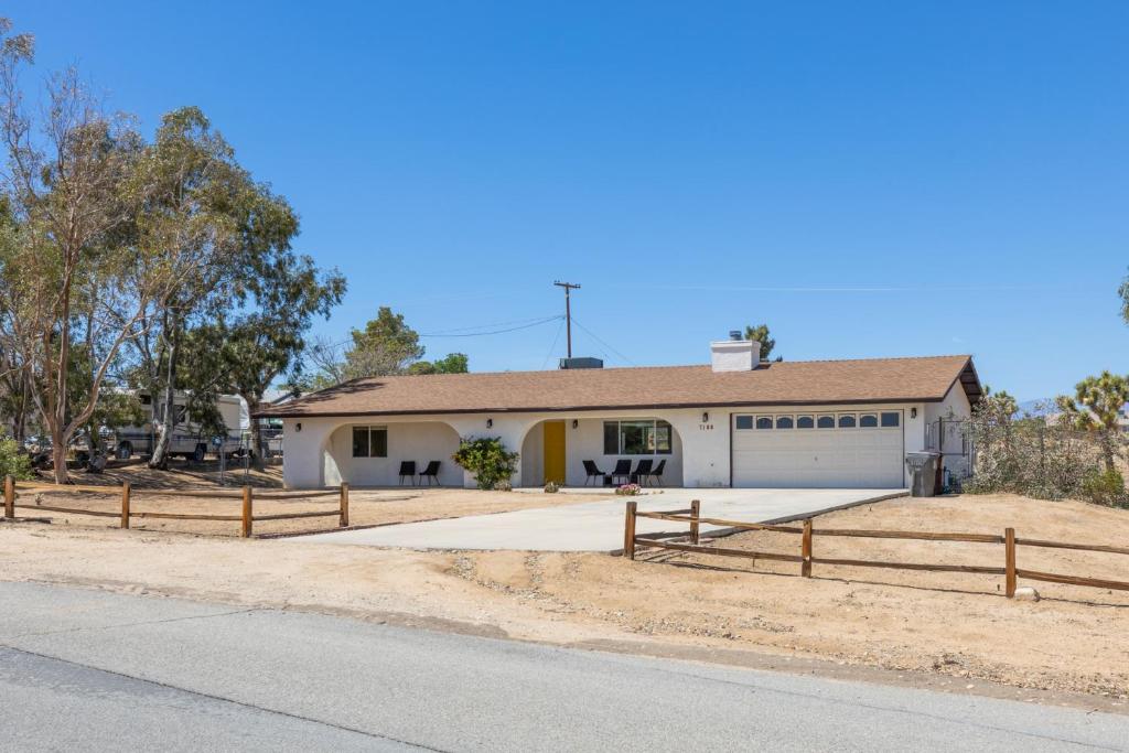 a white house with a fence in front of it at Horseshoe House - Hot Tub, BBQ and Fire Pit! home in Joshua Tree