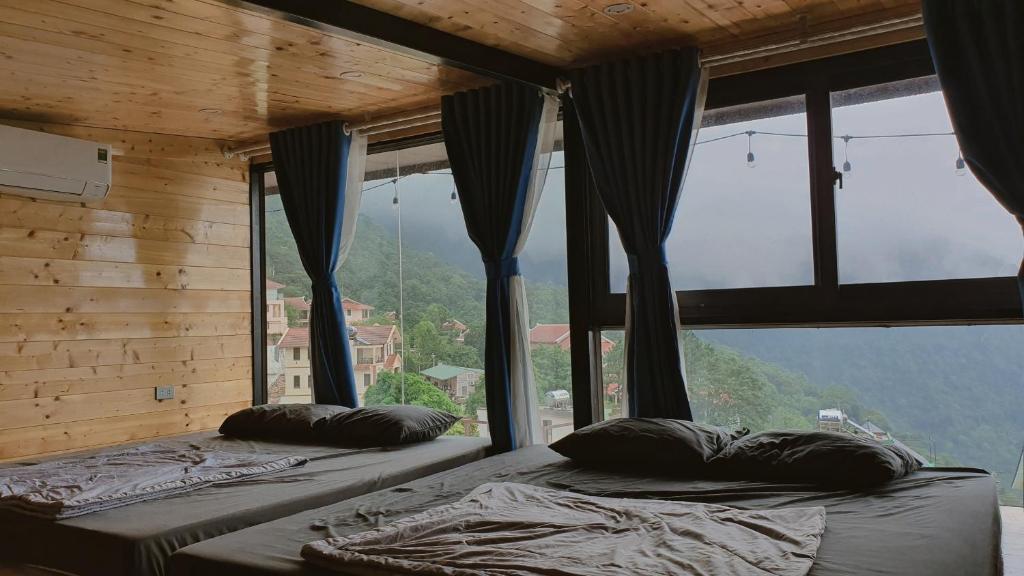 two beds in a room with a large window at Bách Xanh House - Cloud Bungalow in Vĩnh Phúc