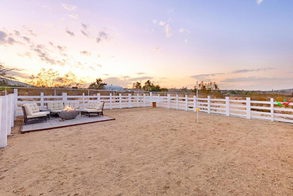 a backyard with a white fence and a table and chairs at Golden Desert Ranch - Hot Tub, Fire Pit and BBQ! home in Joshua Tree