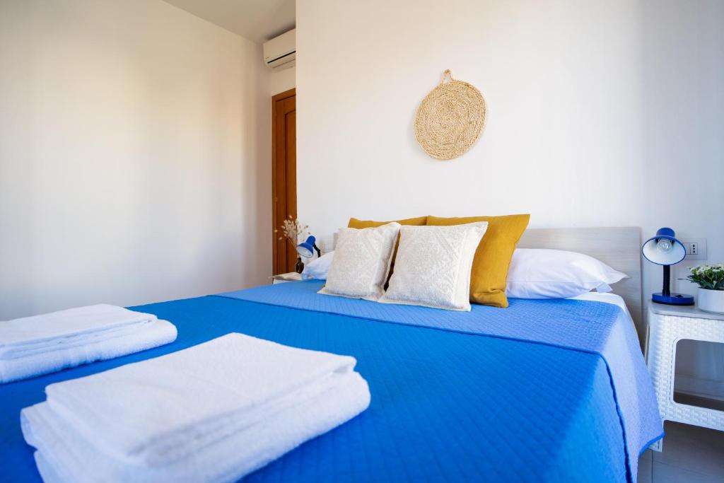 una camera con 2 letti con lenzuola blu e cuscini gialli di Porto Frailis 2 a Tortolì