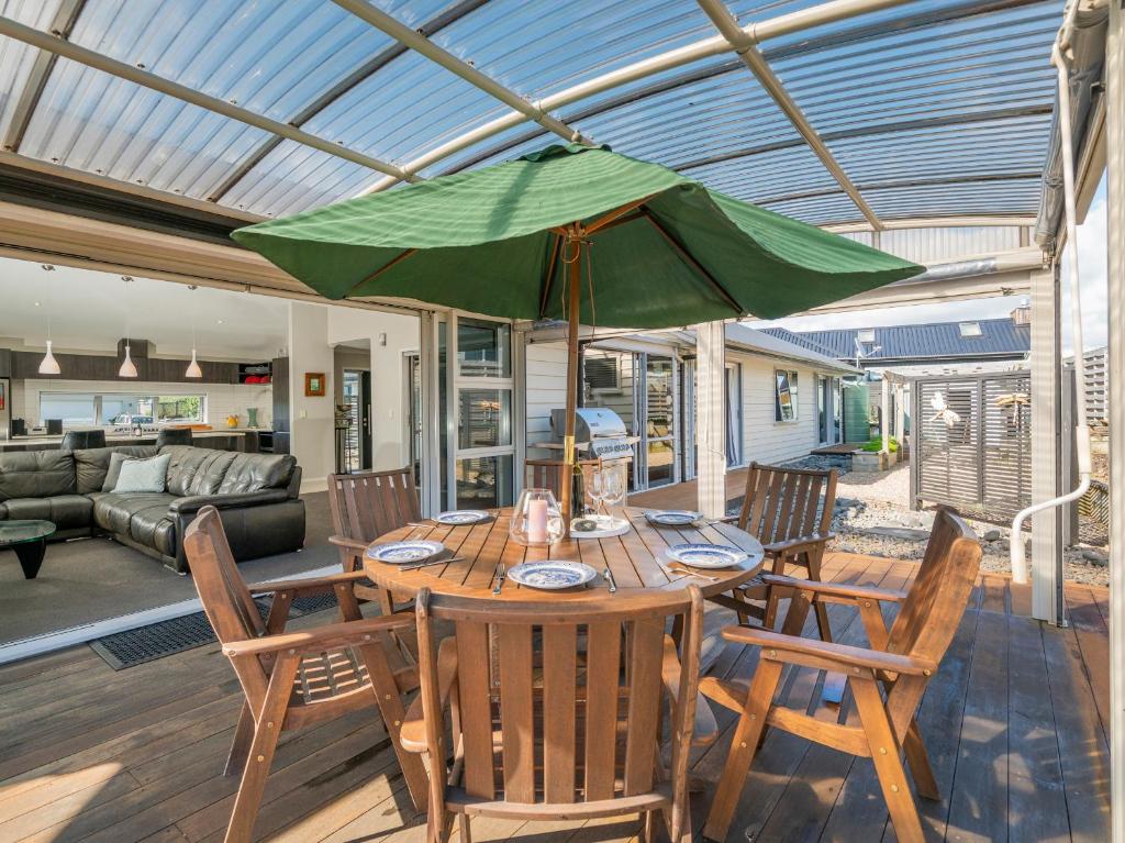 a table with a green umbrella in a living room at Relax on Roseberry - Whitianga Holiday Home in Whitianga