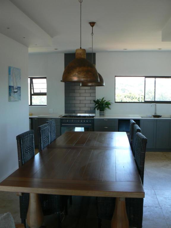 a kitchen with a wooden table with chairs and a stove at The Don Lodge in Amanzimtoti