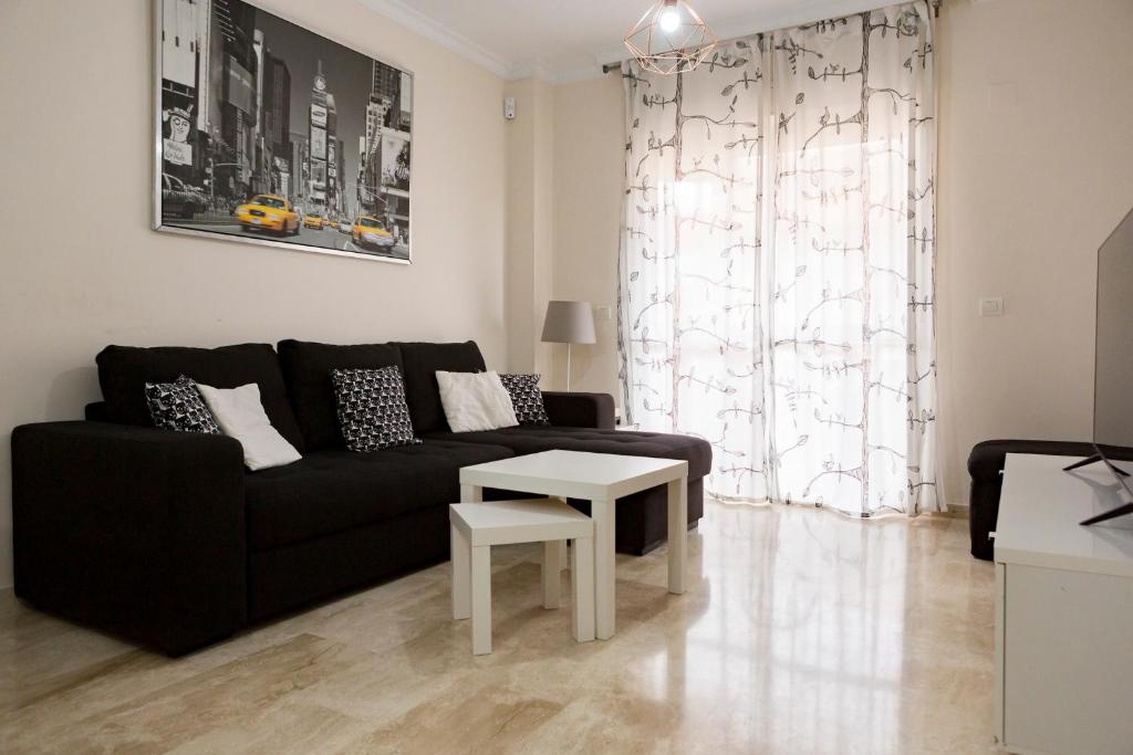a living room with a black couch and a table at Apartamento Málaga Jalón in Málaga