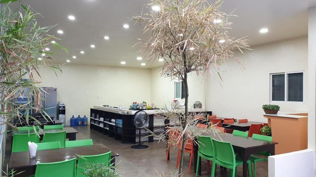 uma sala com mesas e cadeiras verdes e árvores em Harang Hotel Mactan Lapulapu City Cebu Philippines em Maribago