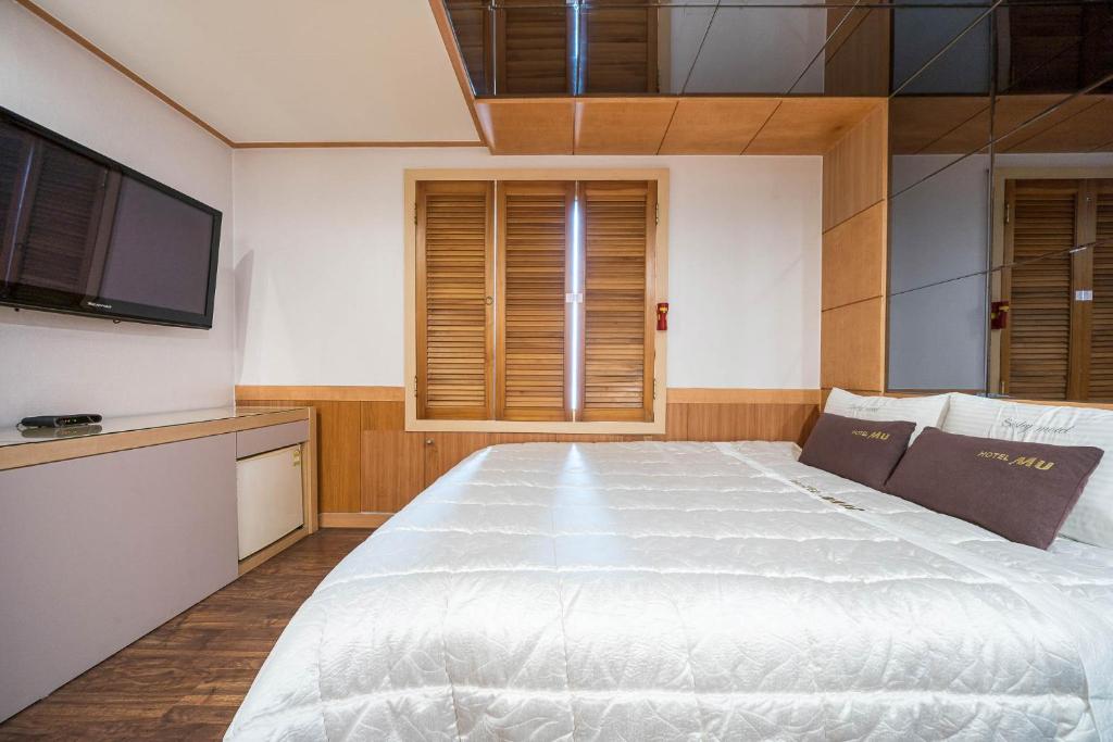 釜山的住宿－MU Hotel Sasang，卧室配有一张白色大床和一台平面电视。