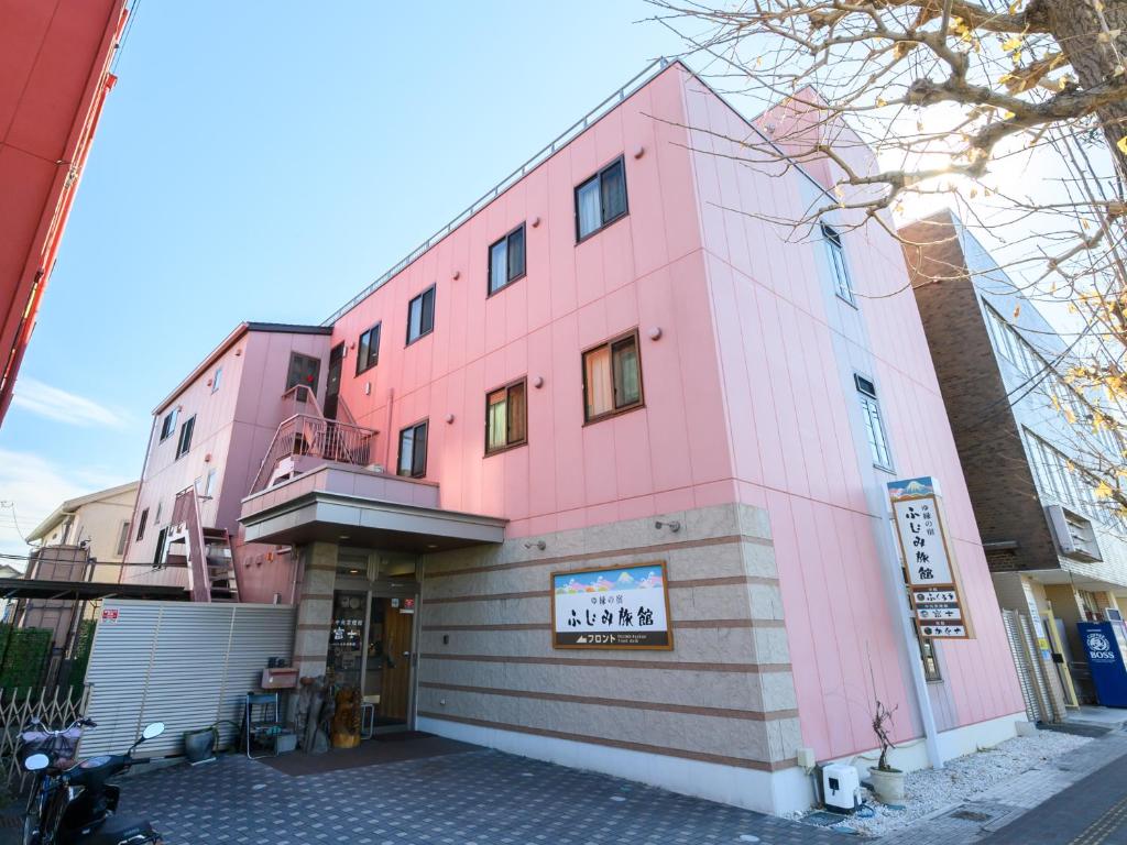un edificio rosa al lado de una calle en Tabist Yuen no yado Fujimi, en Fuji