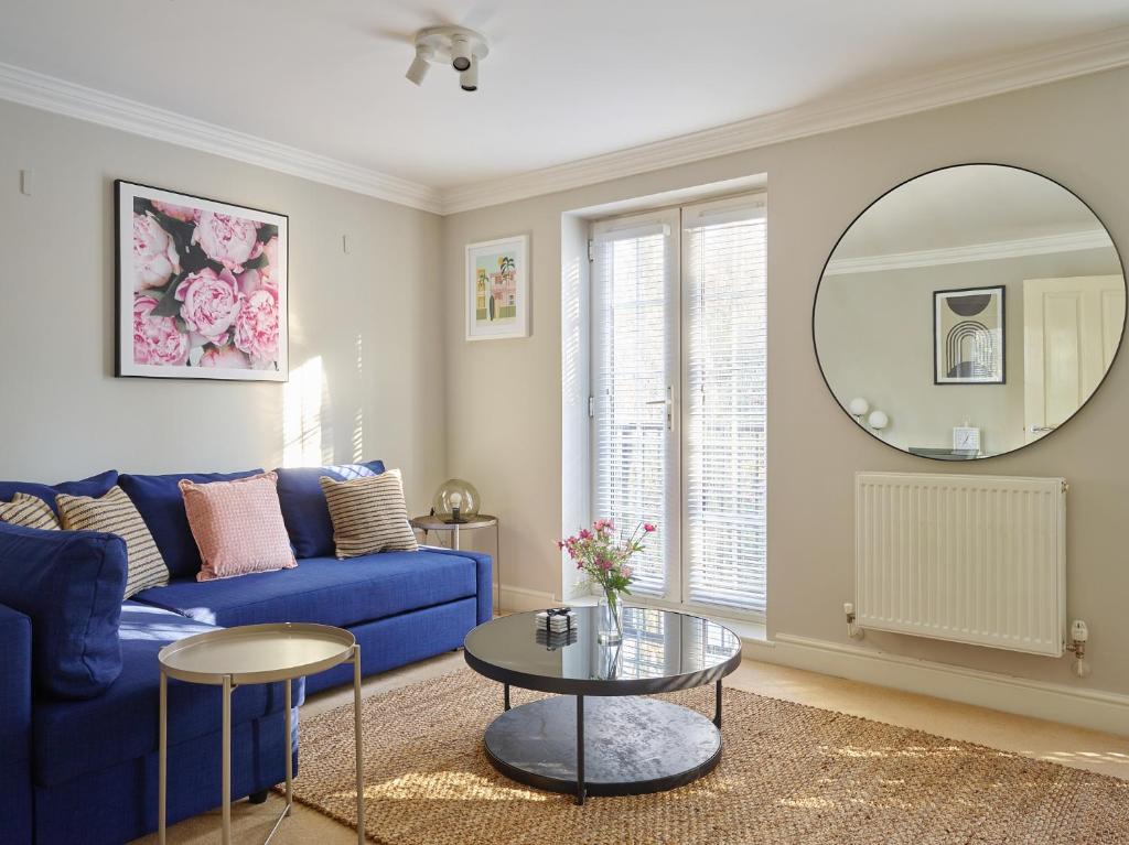 a living room with a blue couch and a mirror at Curb Properties - Gorgeous 3 Bedroom House Close To Town Centre in Cheltenham