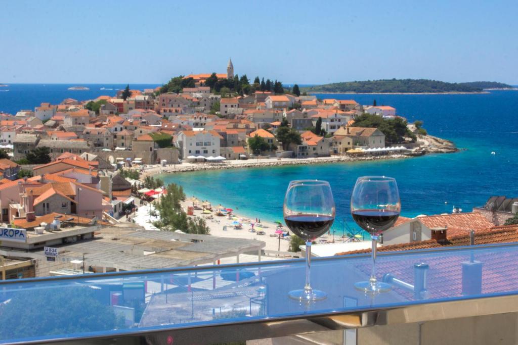 two glasses of wine sitting on a balcony overlooking a beach at Royal Primošten in Primošten