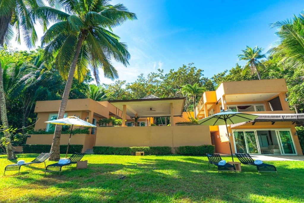 uma casa com um quintal com cadeiras e guarda-sóis em Coral Cove Beachfront Villa - Koh Chang em Ko Chang