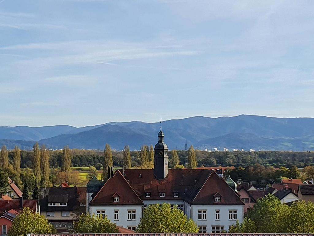 a town with a clock tower and mountains in the background at FeWo Lay in Bötzingen