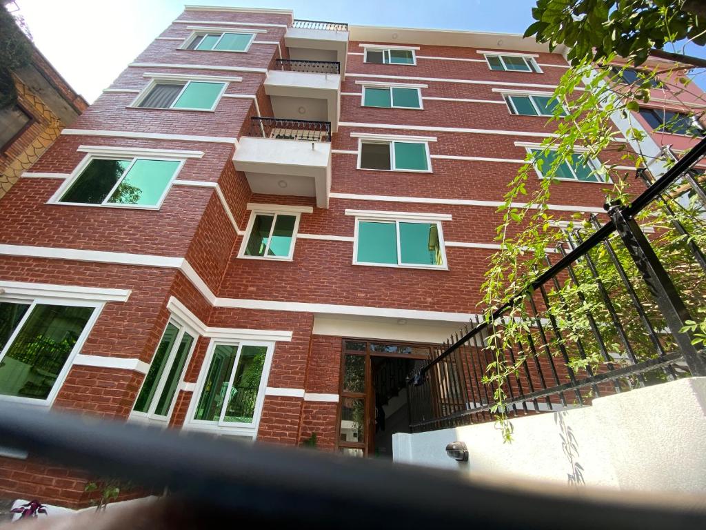 a red brick building with windows and a balcony at Satsang Homestay in Kathmandu