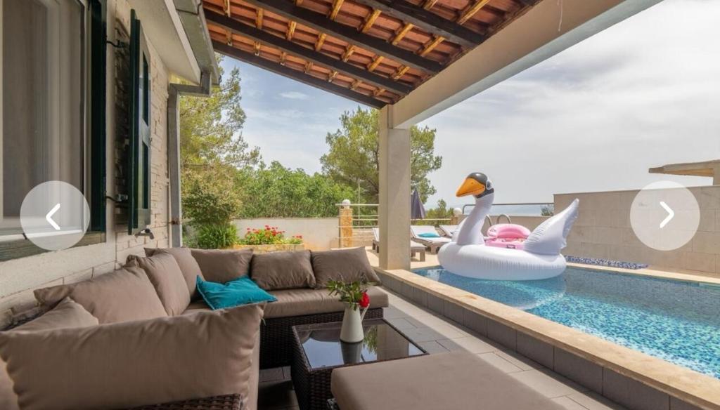 a swimming pool with a swan in the middle of a house at Secluded house with seawater pool in Milna