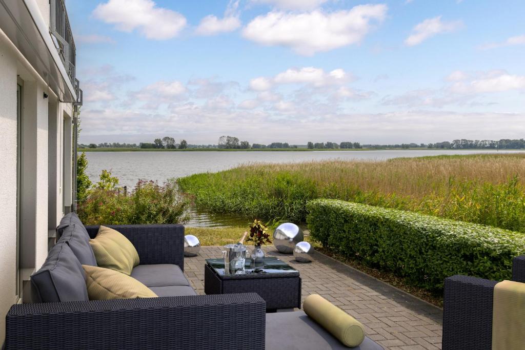 een patio met een bank en uitzicht op het water bij Ferienwohnung Boddenblick in Puddemin