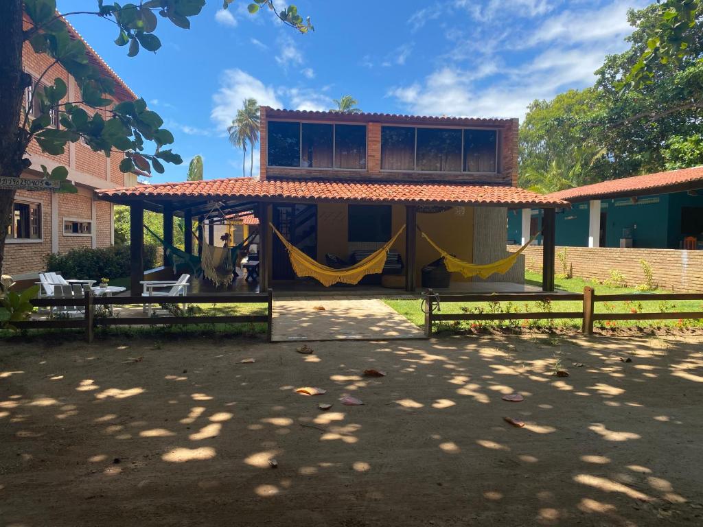 a house with a yellow hammock in front of it at Vila Japaraiso-Casa Amarela Próxima ao mar in Japaratinga