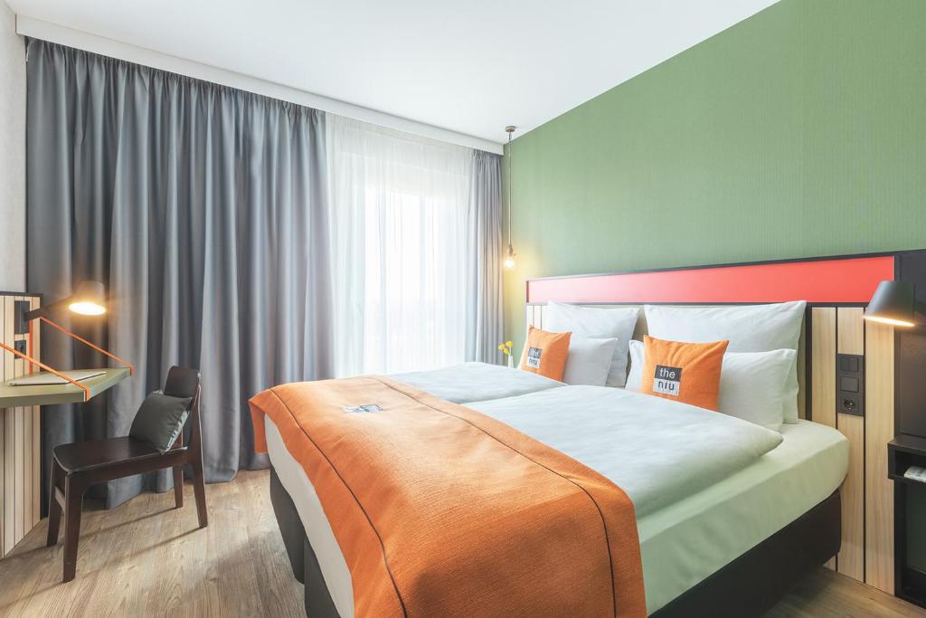 ein Hotelzimmer mit einem großen Bett und einem Stuhl in der Unterkunft the niu Amity in Potsdam