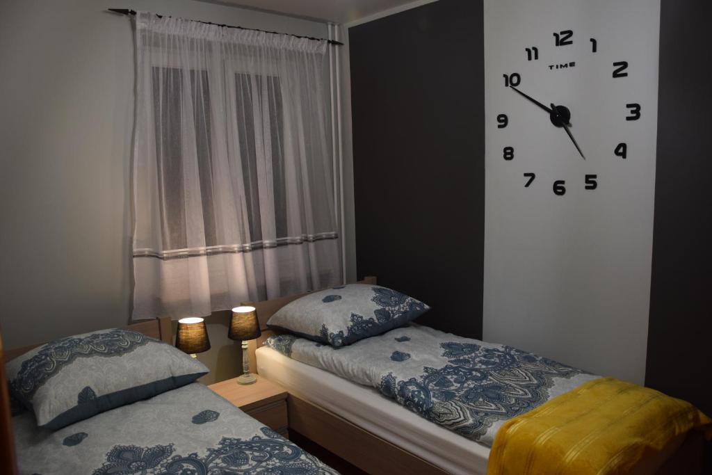a bedroom with two beds and a clock on the wall at Apartament Julia 1-6 os II piętro in Kielce