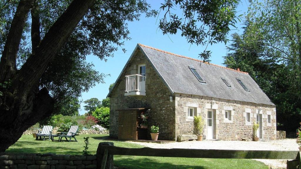 une maison en pierre avec deux chaises devant elle dans l'établissement Gîte Les 3 Voiles, à Ploumilliau