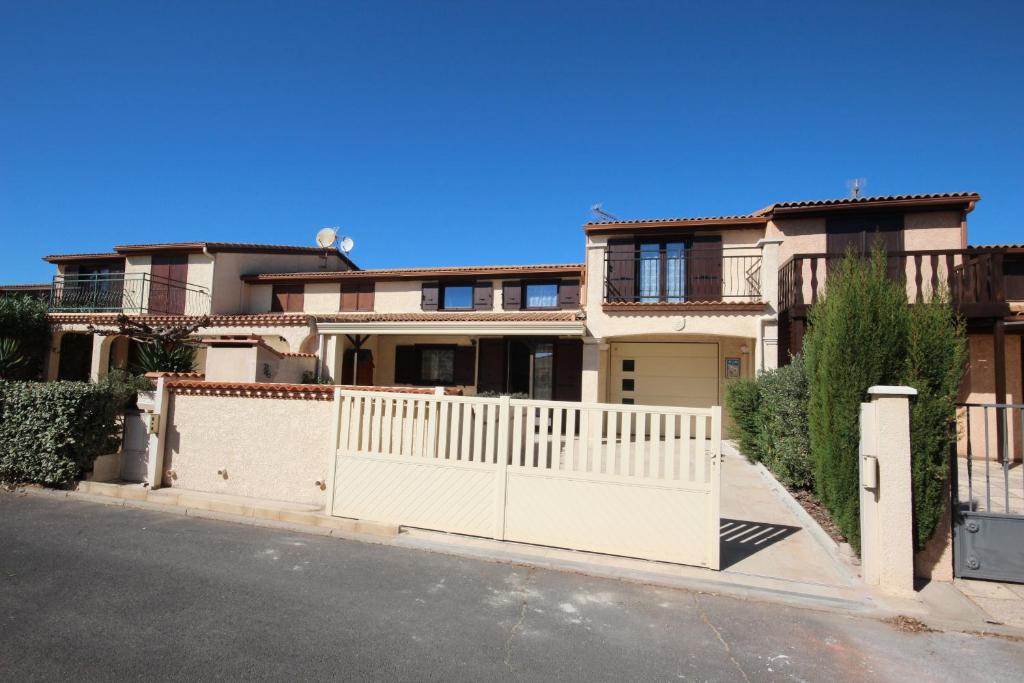 une maison avec une clôture blanche en face d'une rue dans l'établissement Domaine de vacances à 600m de la plage, belle villa climatisée 3 chambres, 5 couchages terrasse WIFI, accès payant pour les animations et piscines LRPDSE3, à Portiragnes