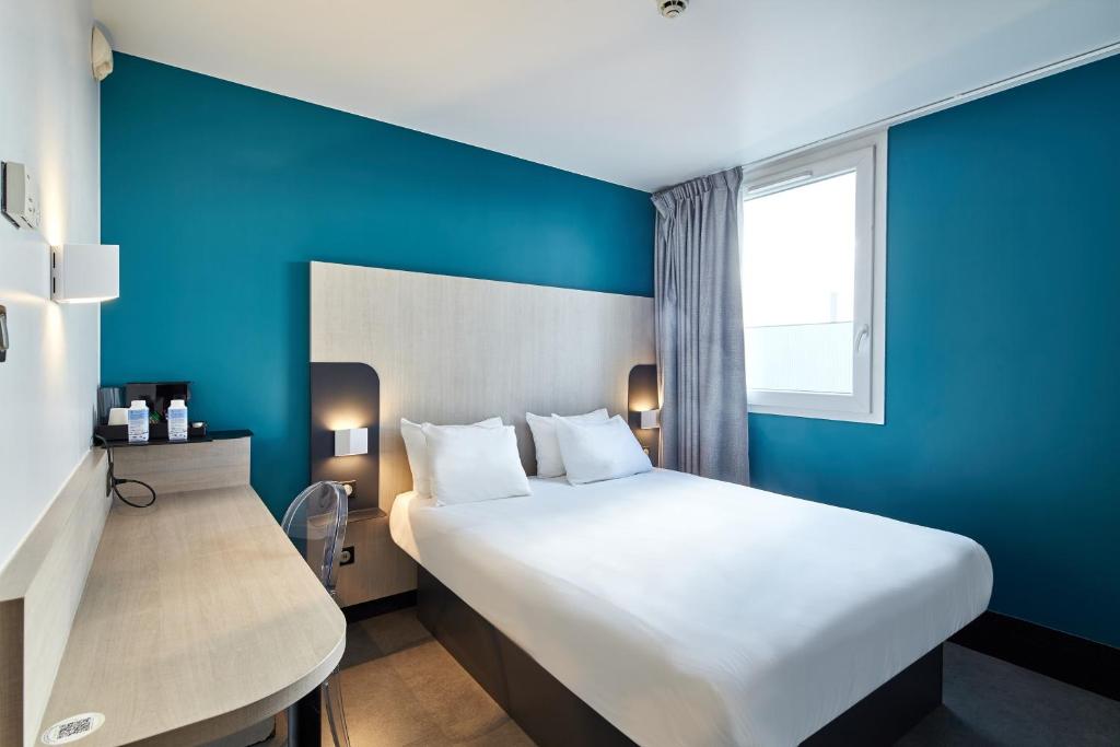 a hotel room with a large bed and a blue wall at B&B HOTEL Paris Nord Gonesse Parc des Expos in Gonesse