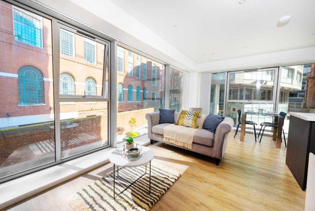 uma sala de estar com um sofá e janelas grandes em Brand New Luxury 1-Bed Apartment in Liverpool em Liverpool