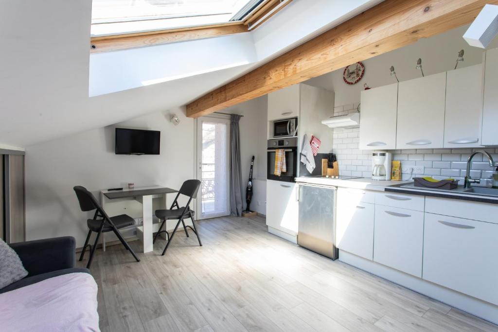 a kitchen with white cabinets and a table with chairs at Le Coq Charmant petit studio en centre ville d'Embrun in Embrun