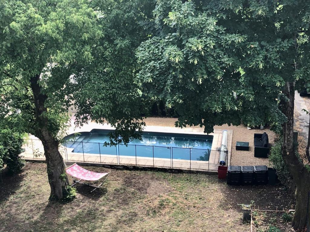 een zwembad met een bank en een boom bij La Grande Maison Mazamet in Mazamet