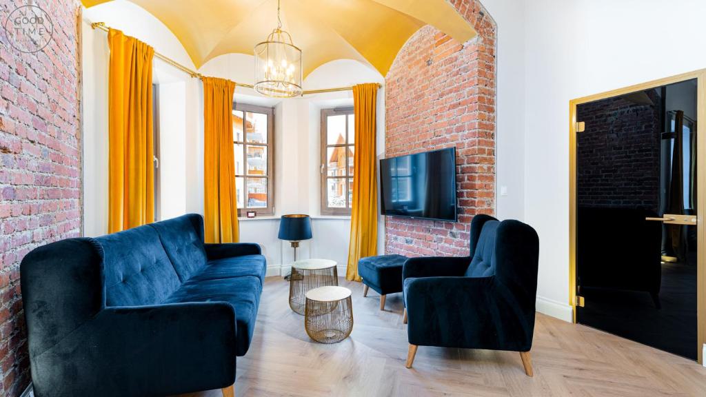 a living room with two blue chairs and a brick wall at Apartamenty Good Time - Stone Hill III in Szklarska Poręba