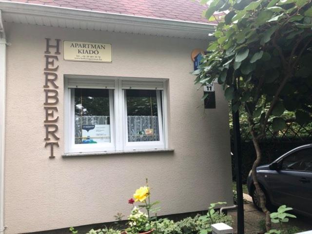 a sign on the side of a house with a window at Herbert Apartman in Bük