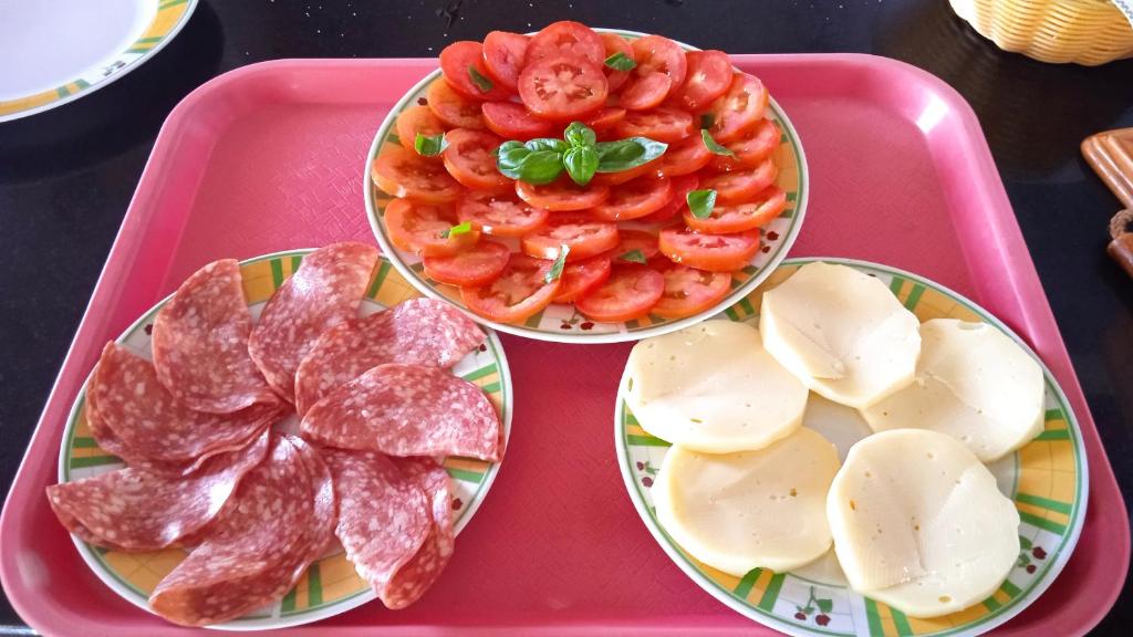 a pink tray with three plates of meat and tomatoes at Astra in Agerola