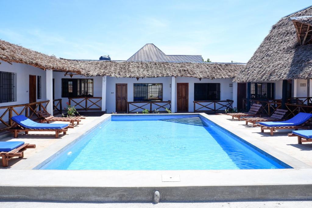 a swimming pool in front of a house with chairs at Nungwi Heritage Resort in Nungwi